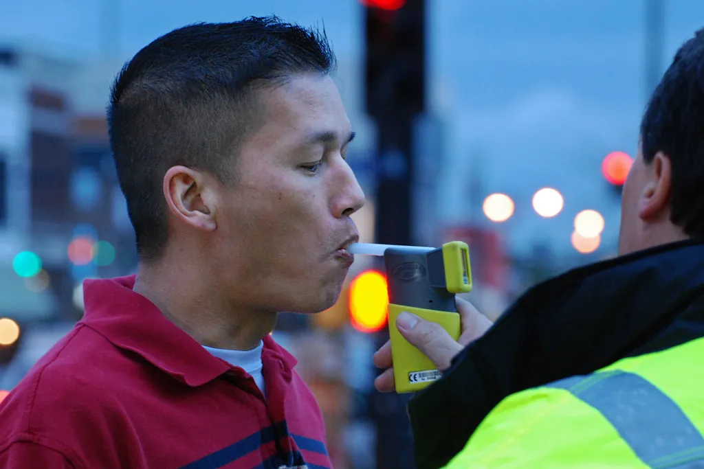 Un hombre sopla un alcotest que le acerca un fiscalizador con chaleco reflectante