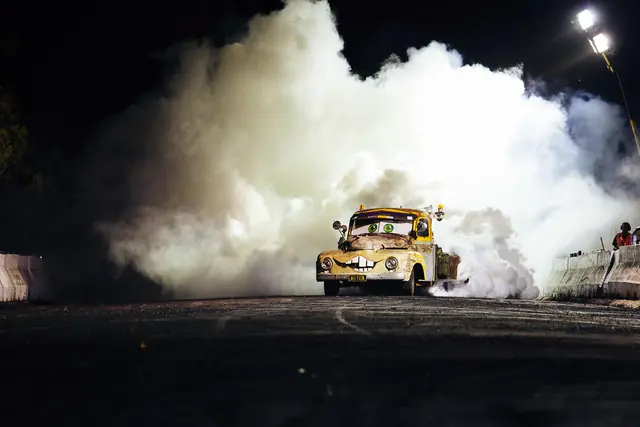 Auto quemando neumáticos de noche entre una gran nube de humo