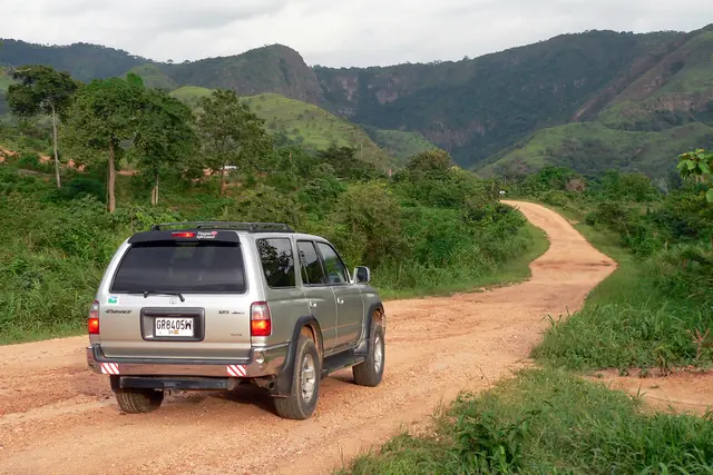Camioneta recorriendo un camino de tierra entre cerros verdes durante un viaje